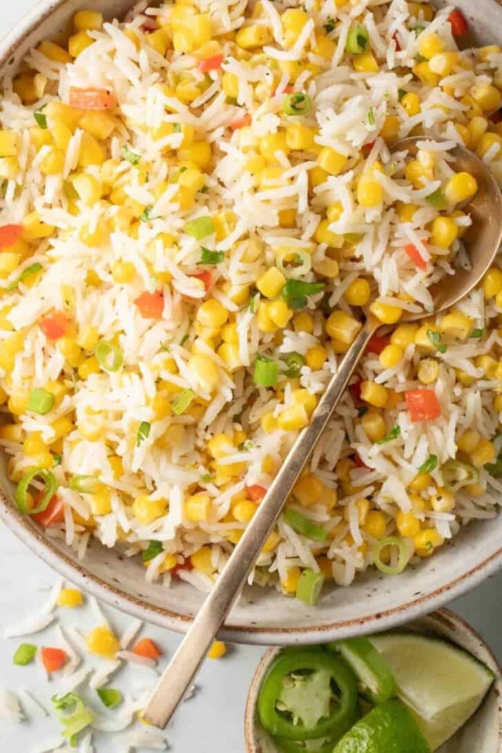 Rice and Corn Recipe Mexican Rice and Corn mixed in a bowl with a spoon.
