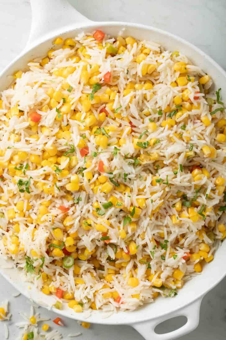 Corn Rice Recipe Fluffy Corn Rice in a white skillet.