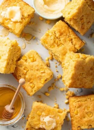 Southern Cornbread cut into squares with a jar of honey.
