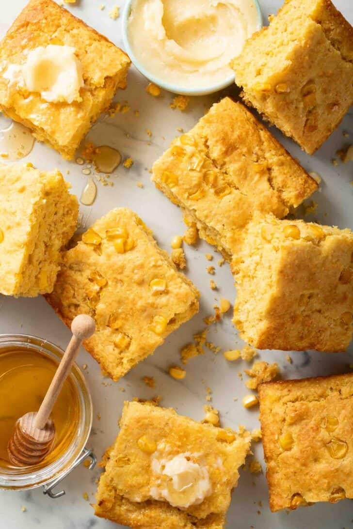 Southern Cornbread Recipe Cut squares of Southern Cornbread on a marble counter with butter and honey.