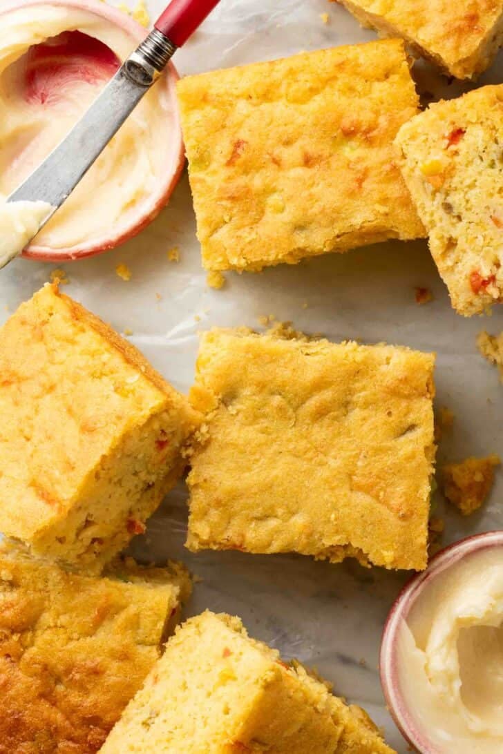 Cornbread with Creamed Corn Mexican Cornbread cut into squares next to small bowls filled with honey butter.