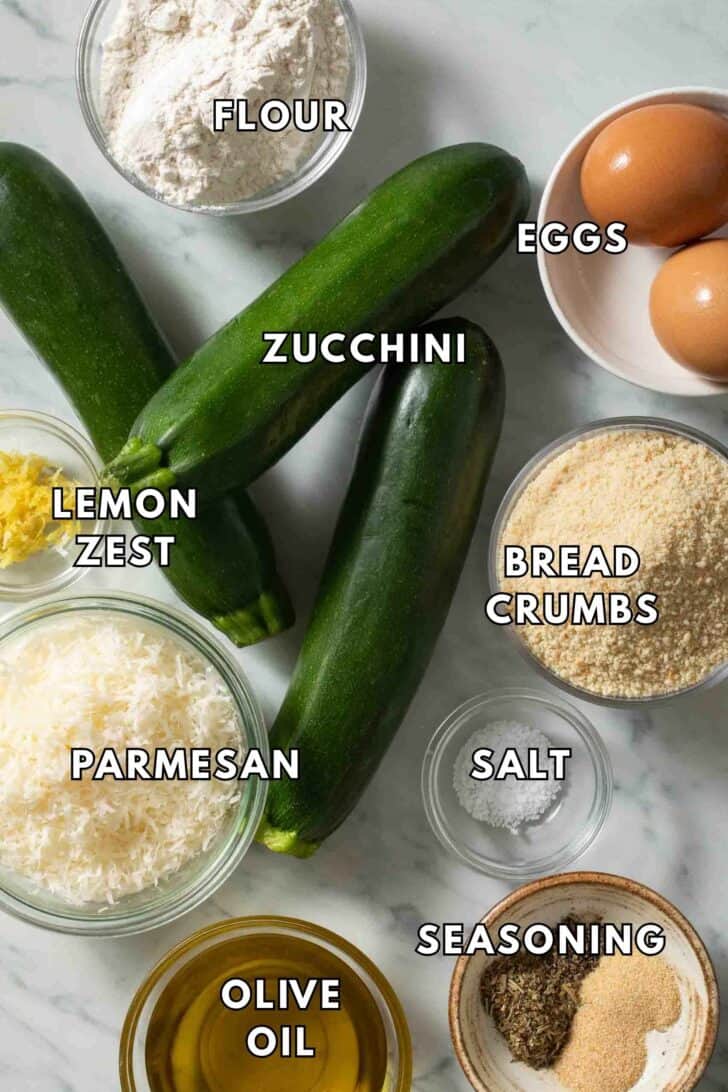 Zucchini Fries Recipe Ingredients for zucchini fries. Whole zucchini and small bowls of bread crumbs, flour and parmesan cheese.
