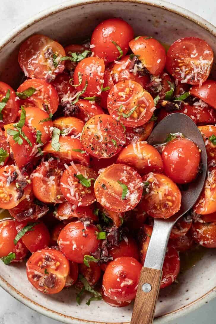 Marinated Tomatoes Recipe Marinated Tomatoes in a bowl with a spoon.