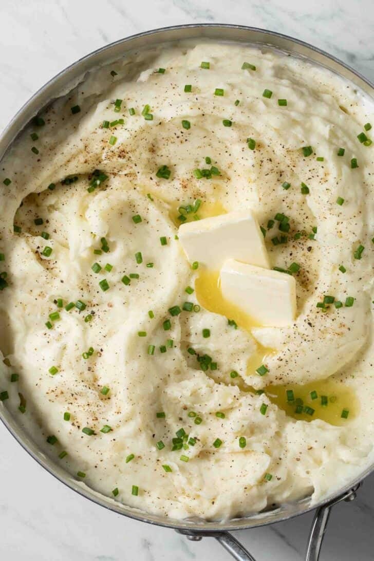 Mashed Potatoes with Sour Cream Mashed Potatoes with Sour Cream in a pot with melted butter and snipped chives.