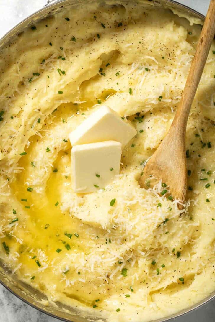 Garlic Parmesan Mashed Potatoes Garlic Parmesan Mashed Potatoes in a pot with a wooden spoon.