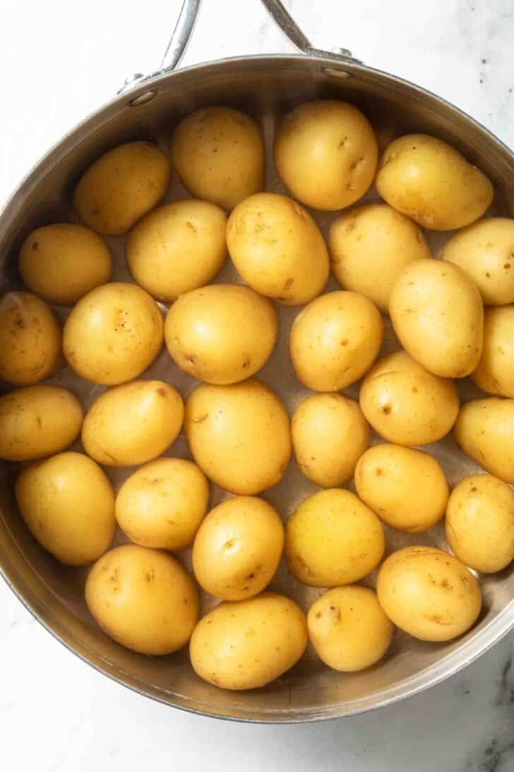 How to Boil Potatoes Baby Yukon Gold potatoes covered with water in a pot for how to boil potatoes recipe.