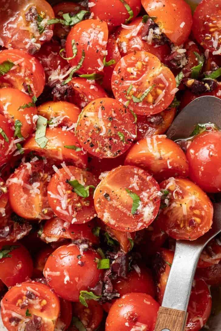 Marinated Tomatoes Recipe Marinated Tomatoes in a bowl with a spoon.
