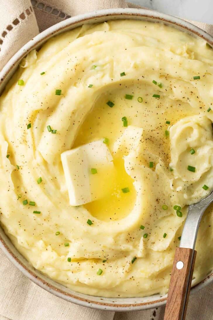 Golden Yukon Mashed Potatoes Golden Yukon Mashed Potatoes in a bowl with melted butter and a serving spoon.