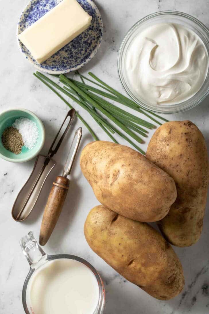 Sour Cream Mashed Potatoes Recipe Russet potatoes, next to a bowl of sour cream, milk and a stick of butter for Sour Cream Mashed Potatoes recipe.