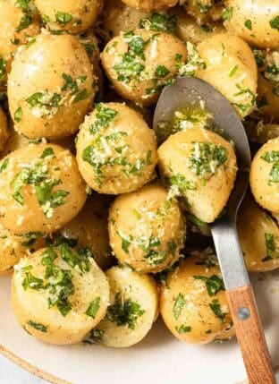 Parsley Potatoes in a bowl with a serving spoon.