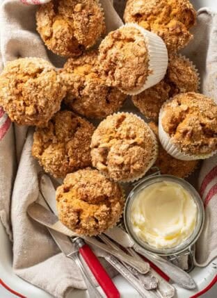 Pumpkin Spice Muffins in a tray with a crock of butter.