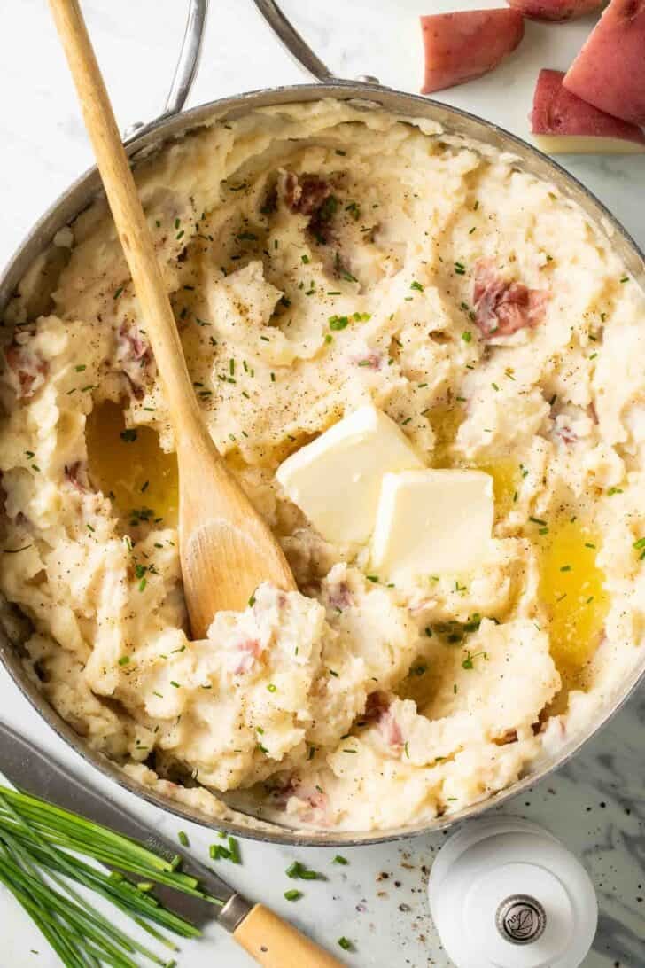 Mashed Red Potatoes Mashed Red Potatoes in a pot with a wooden spoon.