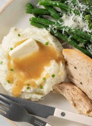 Sour Cream Mashed Potatoes with gravy on a plate.