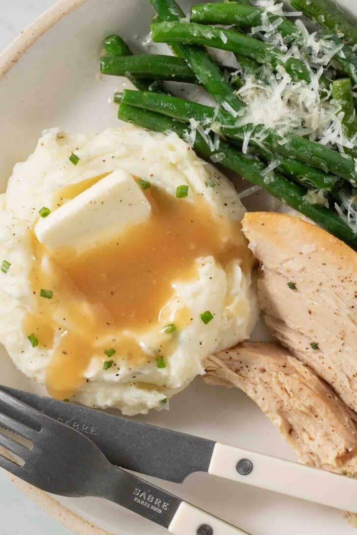 Sour Cream Mashed Potatoes Sour Cream Mashed Potatoes with gravy on a plate.