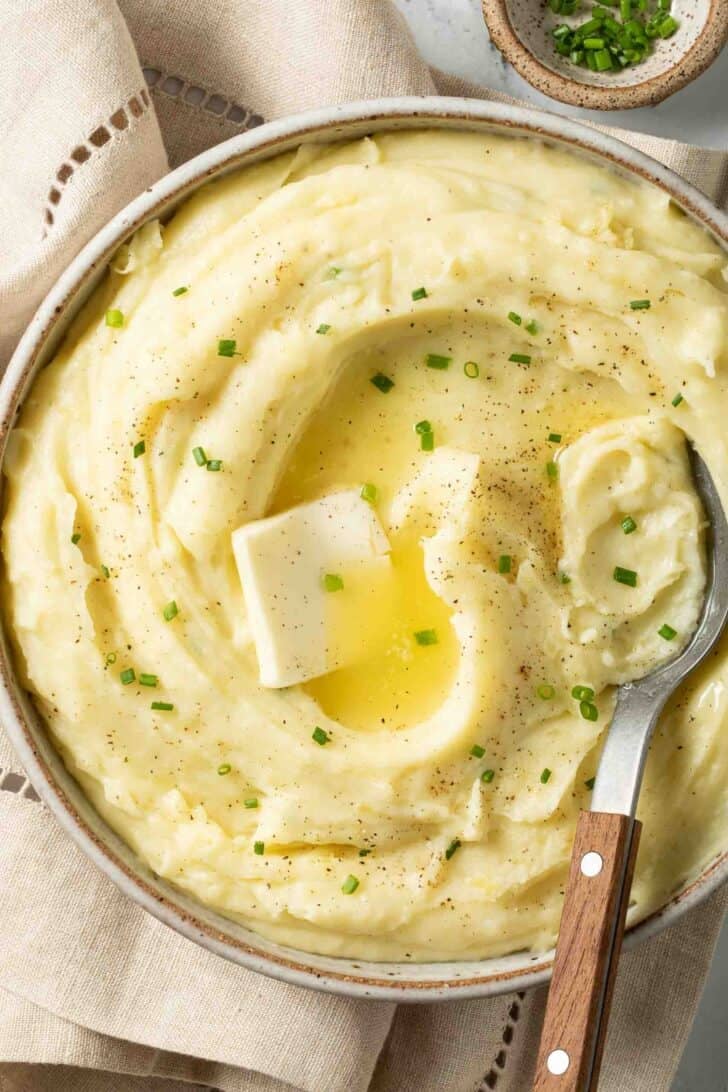Yukon Gold Mashed Potatoes Yukon Gold Mashed Potatoes with melted butter in a bowl and a serving spoon.