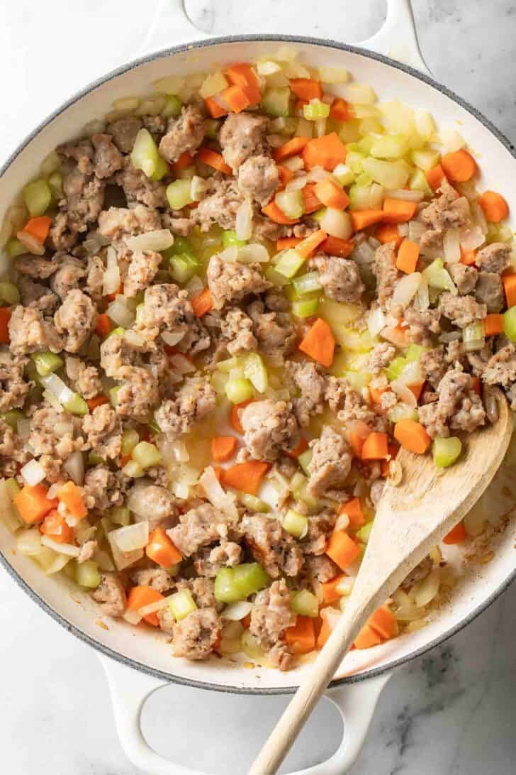 How to Cook Sausage and Vegetable Soup Cooked crumbled Italian sausage with carrots, celery and onons in a white Dutch oven.