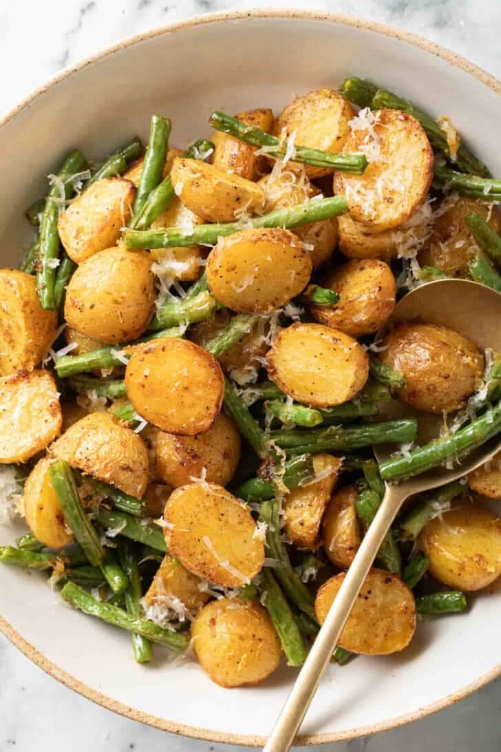 Green Beans and Potatoes Roasted Green Beans and Potatoes in a bowl with a serving spoon.