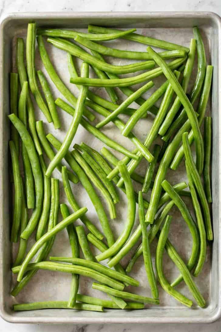 How to Roast Green Beans Fresh green beans on a baking sheet for a roasted green beans recipe.