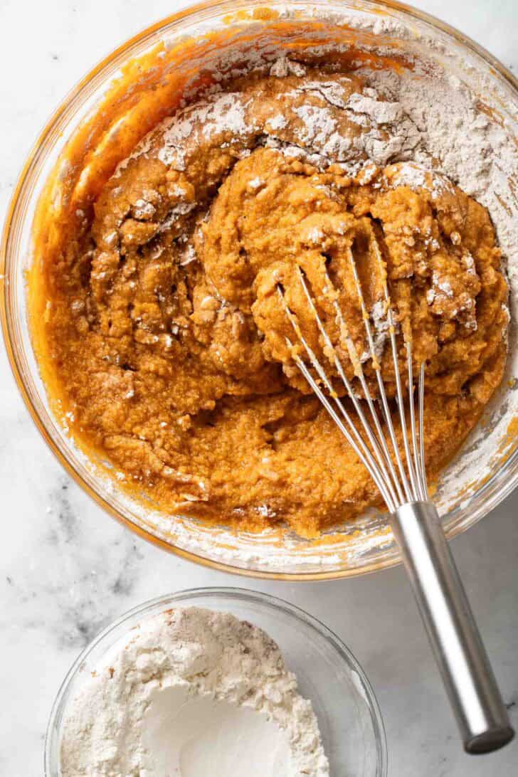How to Make Chocolate Chip Pumpkin Muffins Chocolate Chip Pumpkin Muffin batter in a clear glass mixing bowl.