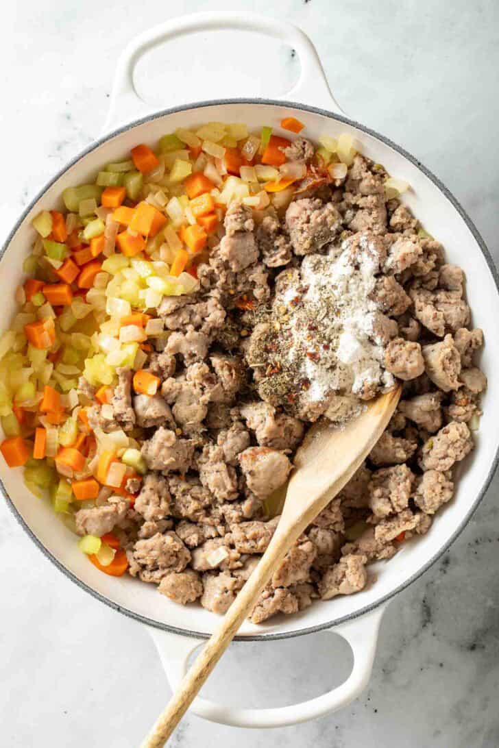 Creamy Parmesan Italian Sausage Ditalini Soup Cooked Italian sausage and vegetables in a white pot.