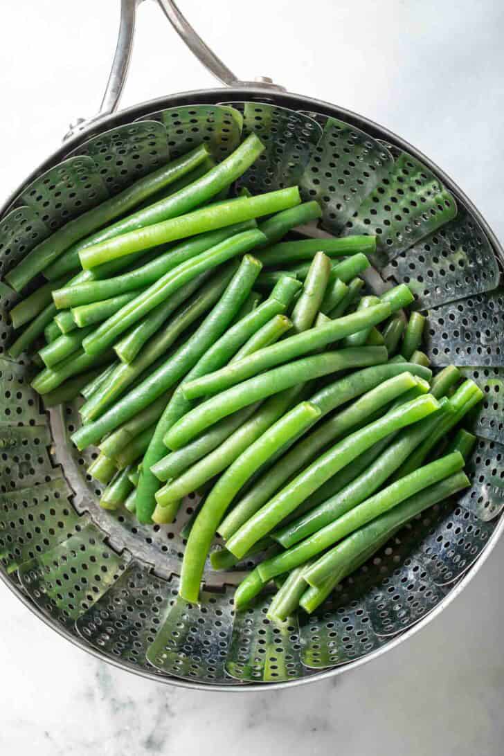 Steamed Green Beans Recipe Fresh green beans in a steamer basket.