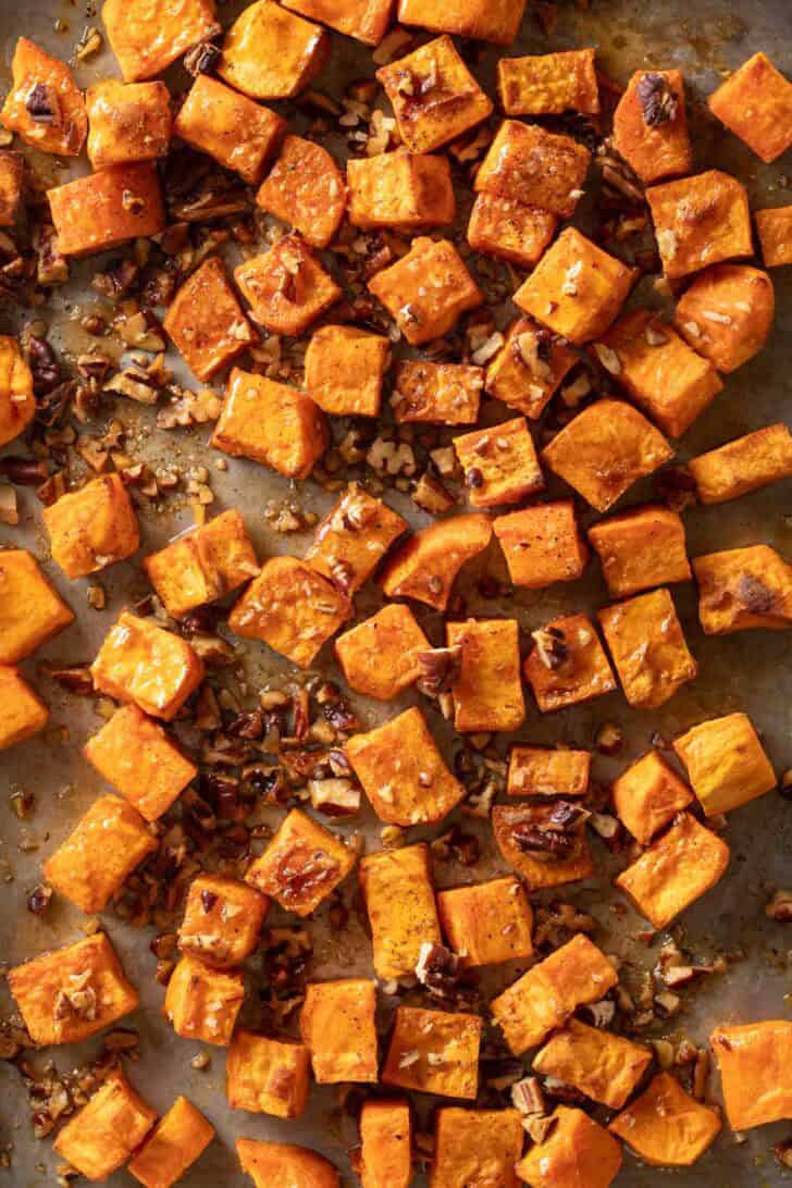 Roasted Sweet Potatoes with Maple Syrup Roasted Sweet Potatoes with Maple Syrup and pecans on a baking sheet.