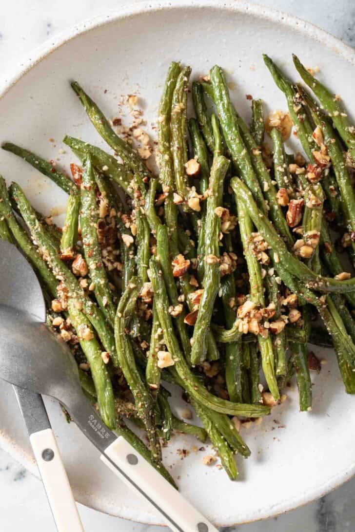 Oven Roasted Green Beans Oven Roasted Green Beans tossed with almonds on a plate.