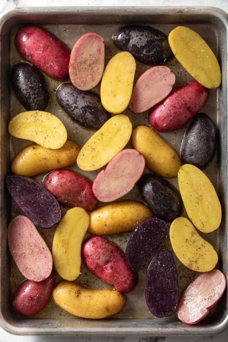 How to Roast Fingerling Potatoes Fingerling potatoes sliced in half lengthwise on a baking sheet.