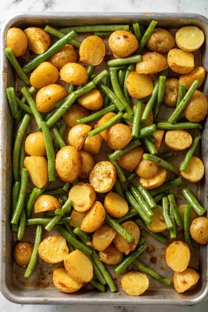 How to Make Green Beans and Potatoes Roasted baby Yukon gold potatoes and green beans on a baking sheet.