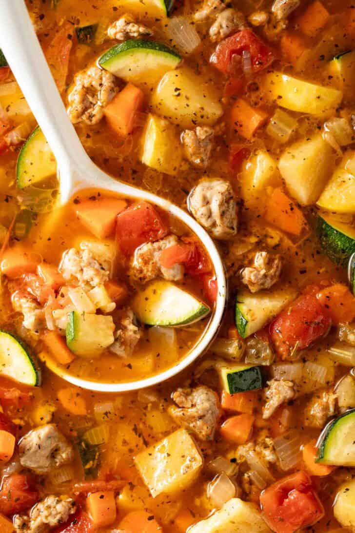 Italian Sausage Soup Italian Sausage Soup in a white Dutch oven with a white ladle.