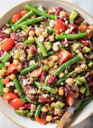 Greek Style Three Bean Salad in a serving bowl with a spoon.