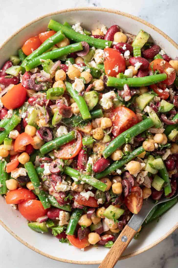 Three Bean Salad Greek Style Three Bean Salad in a serving bowl with a spoon.