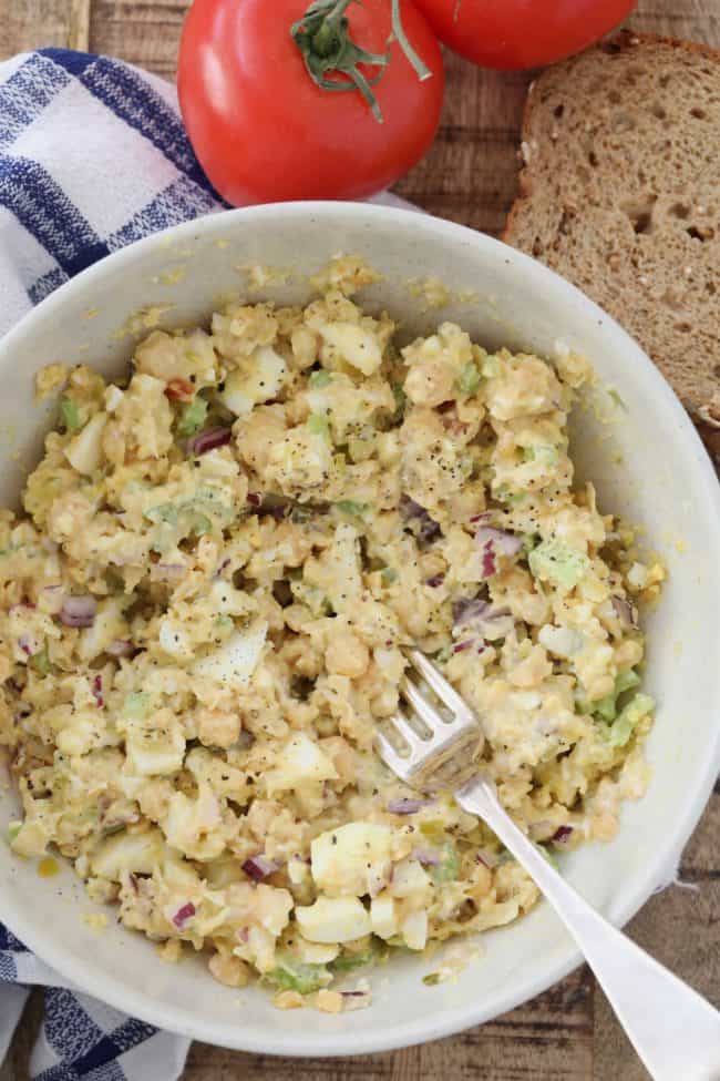 A white bowl filled with chickpea and egg salad.