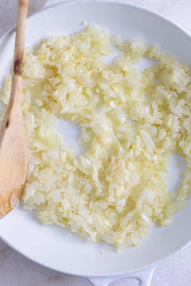 A white skillet filled with cooked chopped onions.